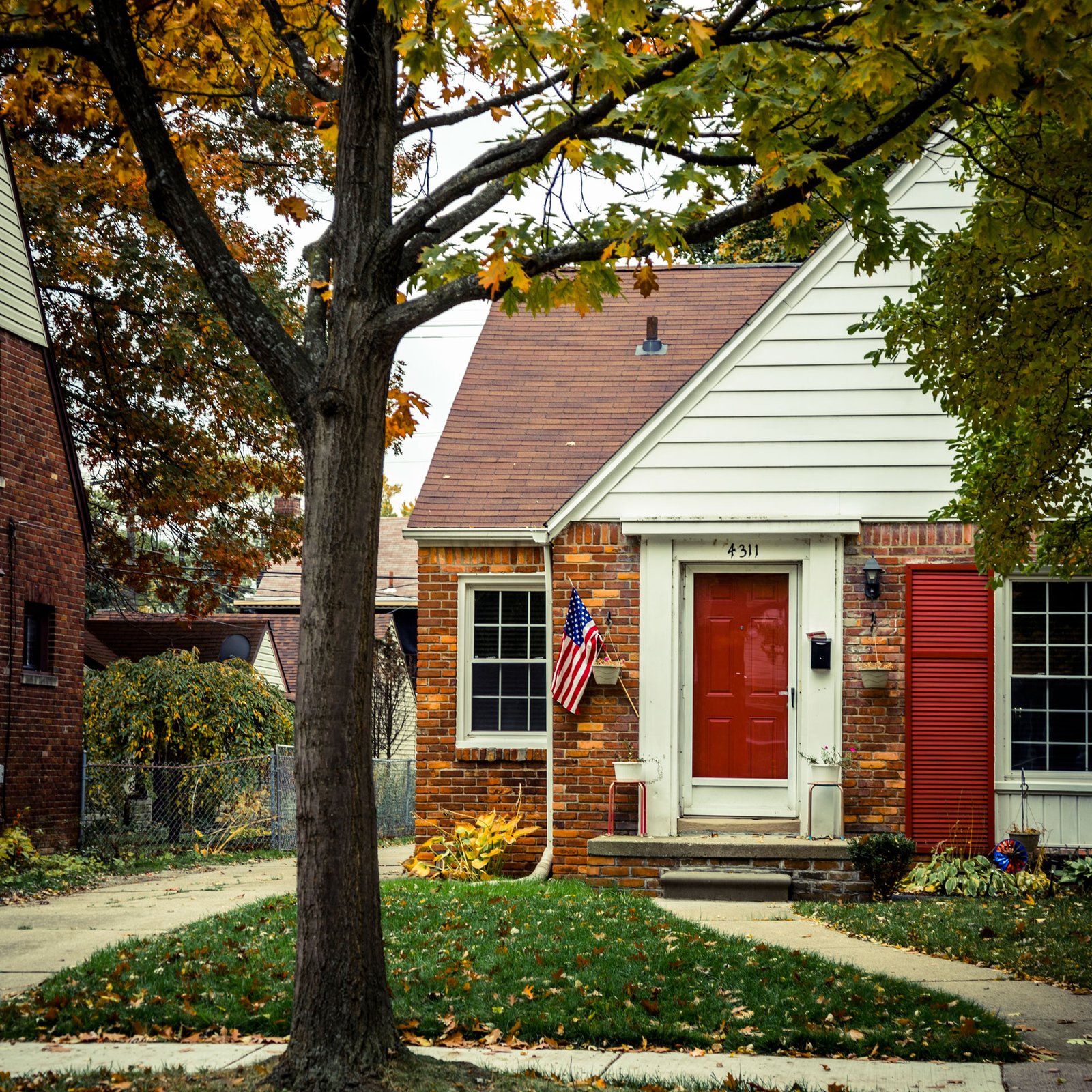 brick house with red front door and US flag